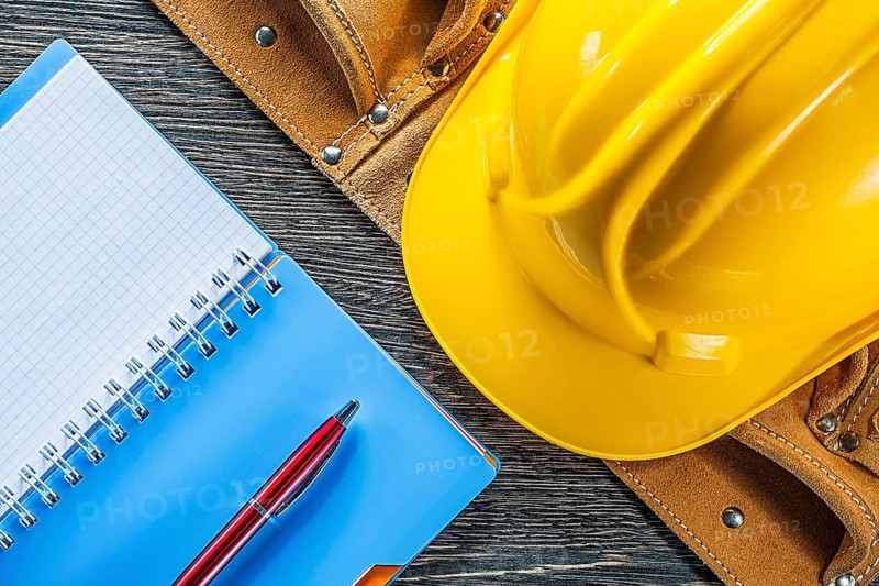 Notebook pen tool belt building helmet on wooden board