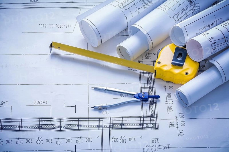 Rolled blueprints compass and yellow tapeline