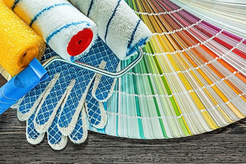 Paint rollers safety gloves color palette on wooden board