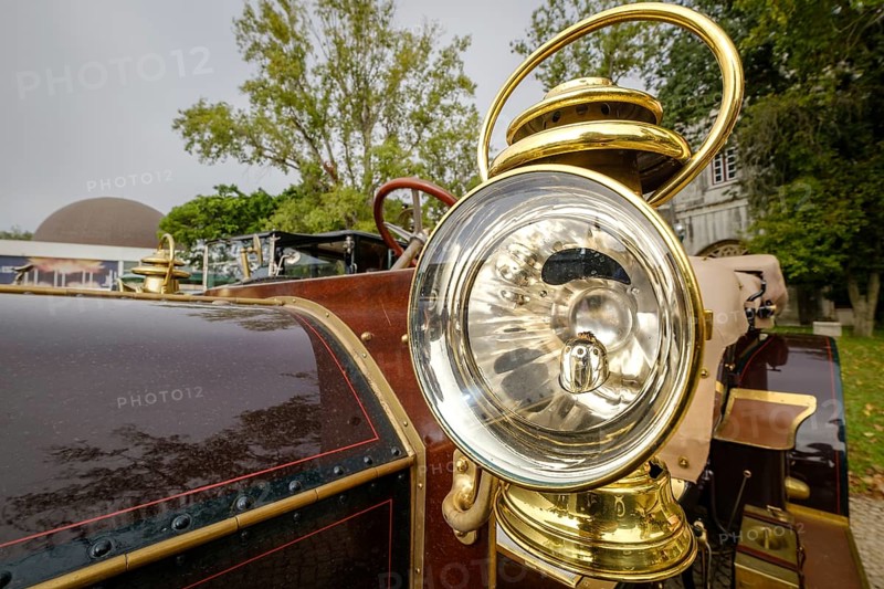 Lisbon, Portugal - Oct 15, 2023: Detail of 1904 Mercedes Simplex - external headlight in brass housing with reflective interior and glass lens. Round shape of antique car lantern-like headlight with incandescent bulb system