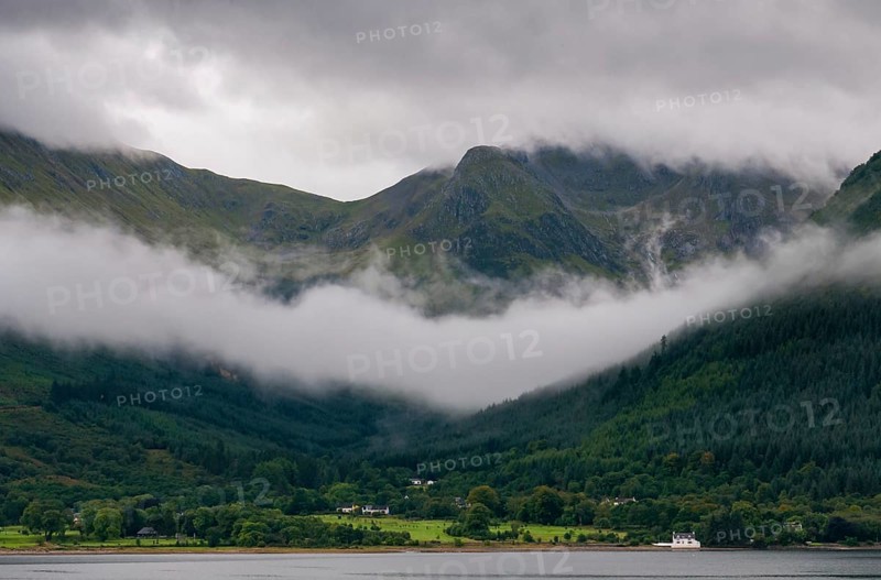 Idyllic mountain landscape with morning early fog covering the peaks at Fort Williams, Glencoe area in the Highlands of Scotland, United Kingdom, Europe