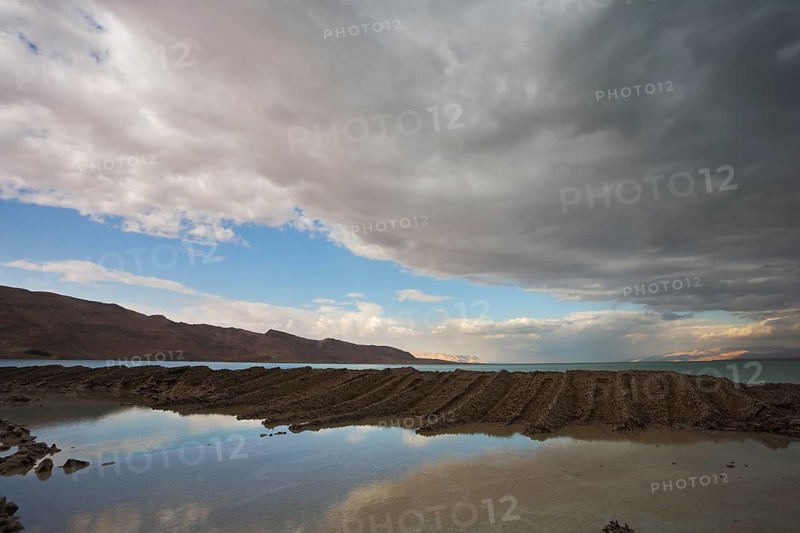 Sunset. Incredible lighting effects on the Dead Sea in Israel. Picturesque sediment mixture of sea salt and mud on the beach