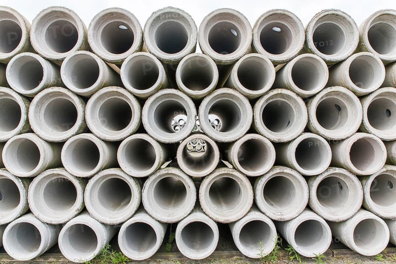 Pile of concrete sewer pipes on concrete plant grounds