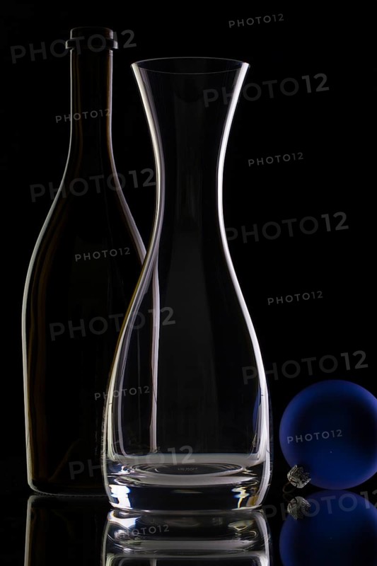 The bottle of wine, glass carafe and Christmas decoration on a black glass desk