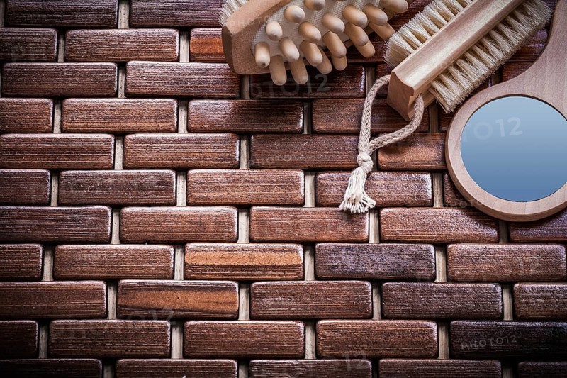 Wood massager looking-glass and peeling brush on textured wooden mat sauna concept