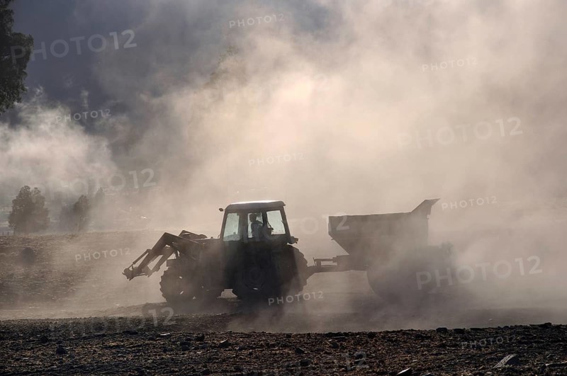 Tractor spreading lime with a fertiliser spreader, West Coast, New Zealand, Oceania