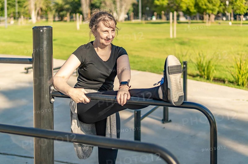 Activating muscles: Mature woman warming up outdoors in an urban park