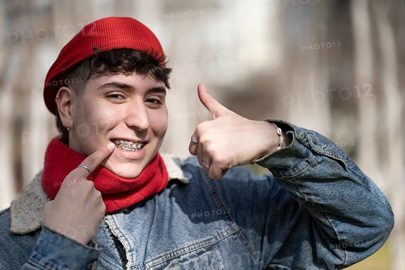 Young man smiling at the camera with thumb up showing his braces