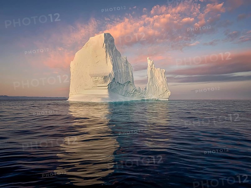 Large glaciers in the bay by the rocky shore in the light of the setting sun