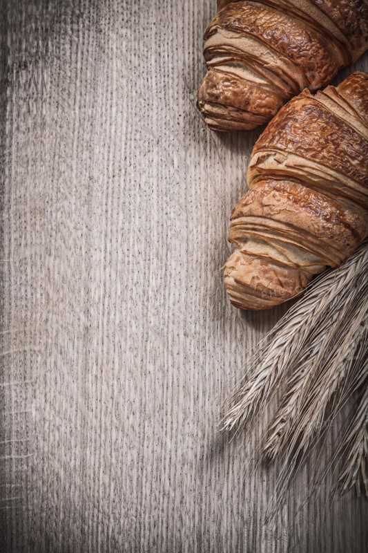 Golden wheat rye ears baked croissants on a wooden board