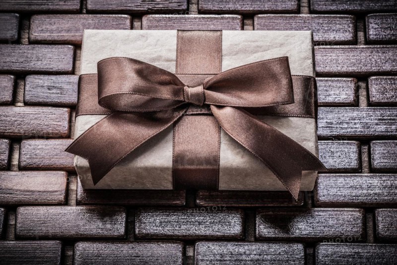 Wrapped giftbox with ribbon on wooden wicker matting holidays concept