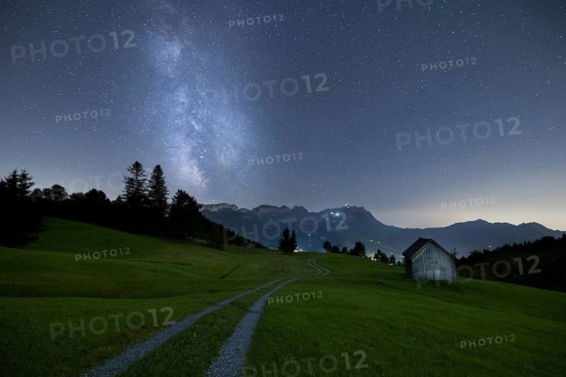 A clear night with a view of the Milky Way over a meadow and a remote hut with a mountain view, Fähnerenspitz, Brülisau, Appenzell Innerrhoden, Switzerland, Europe