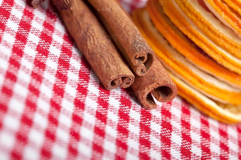 Slices of dried orange and cinnamon sticks on a chequered cloth