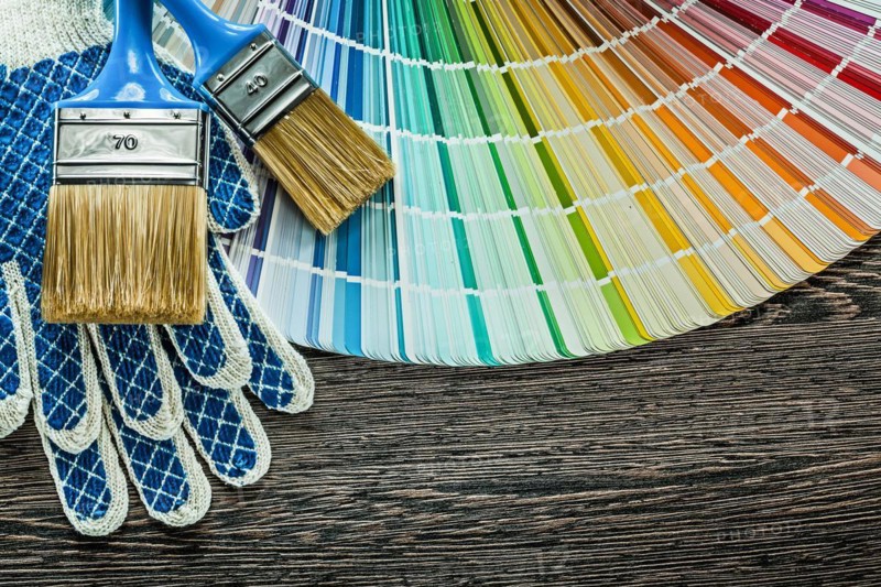 Pair of safety gloves paint brushes color sampler on wooden board