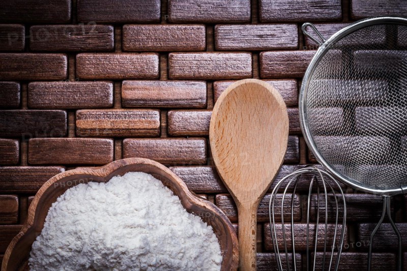Wood spoon bowl flower sieve and egg-whisk on wooden matting