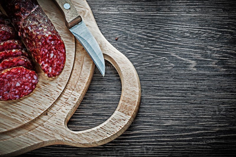 Chopped salami knife on wooden chopping board