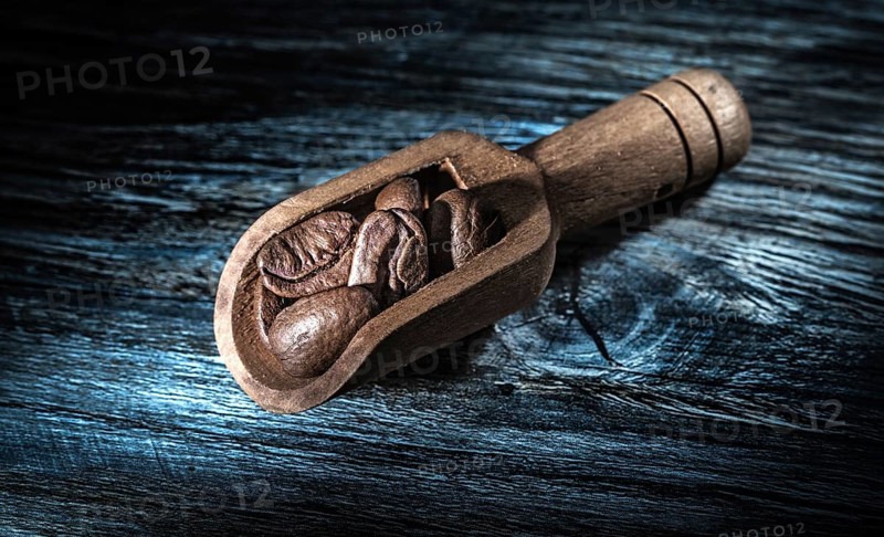 Coffee beans in scoop on wooden board