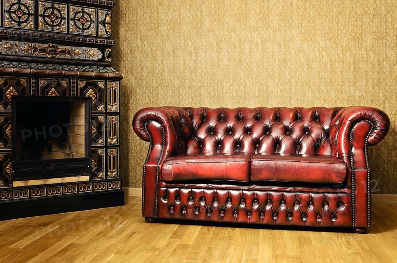 Old Red Genuine Leather Sofa Near The Fireplace