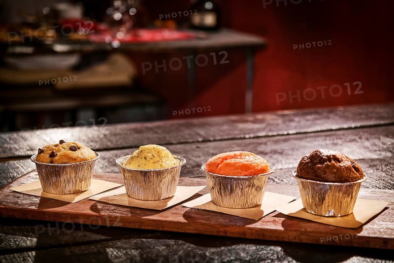 Mixed freshly baked muffins on table in cozy coffeeshop interior