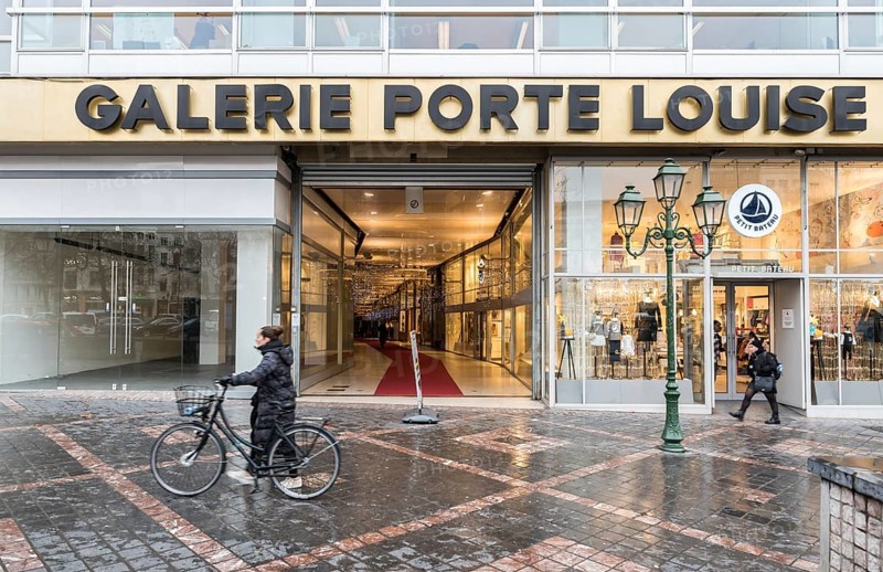 Brussels Old Town, Brussels Capital Region, Belgium, 12 12 2019 Woman with bicycle and pedestrians walking by the Galerie Porte Louise entrance, Europe