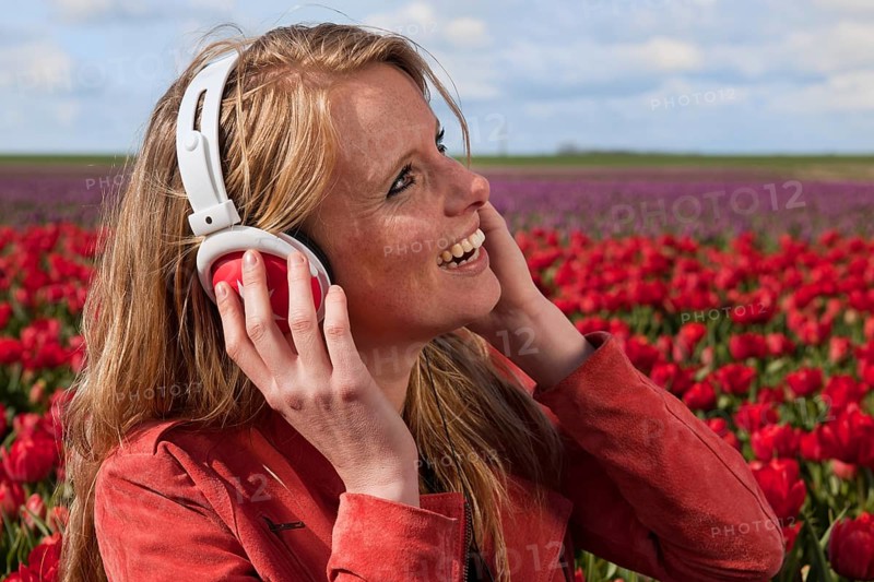 Portrait of a beautiful blond Dutch girl listening to music in tulips field