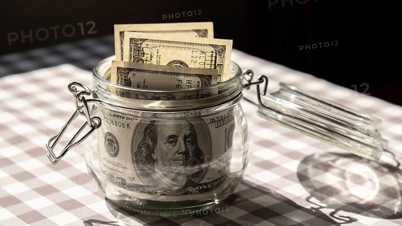 Dollar banknote saving money in glass jar. Consumption and economy Collecting money. Tips. Business, finance, saving, banking and people concept. Extra money, passive income. Saving for travel, crisis, house, car, education, retirement