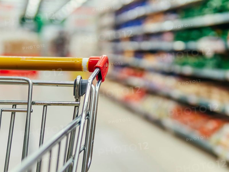 Shopping cart in supermarket. Part of shopping trolley in supermarket aisle. Blurred shelves in grocery store and trolley. Copy space for text or design