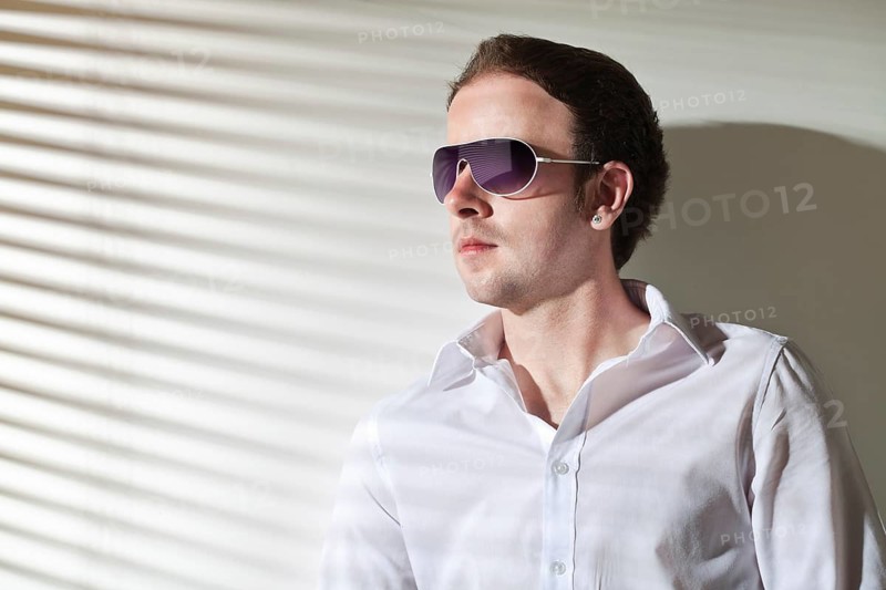 Man in sunglasses looks in the window, stripe shadows from the blinds, Belgium, Europe