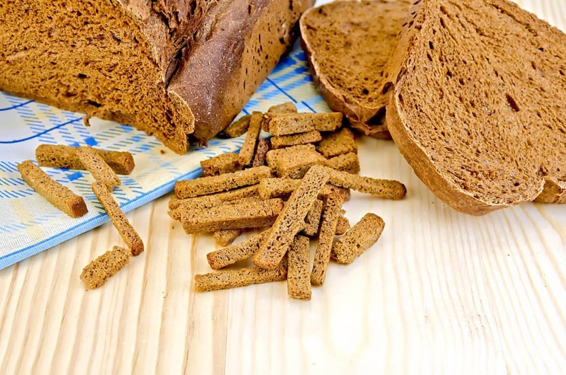 Rye homemade bread, crackers, blue cloth on a background of wooden boards