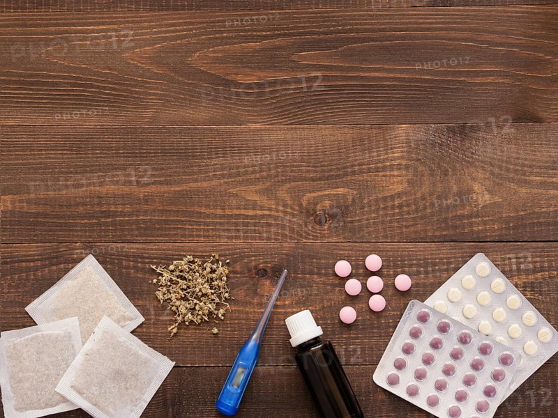 Tablets, drops, herbals and thermometer on a dark wooden background with copy space. Herbal medicine VS Chemical medicine the alternative healthy care. Flat lay or top view