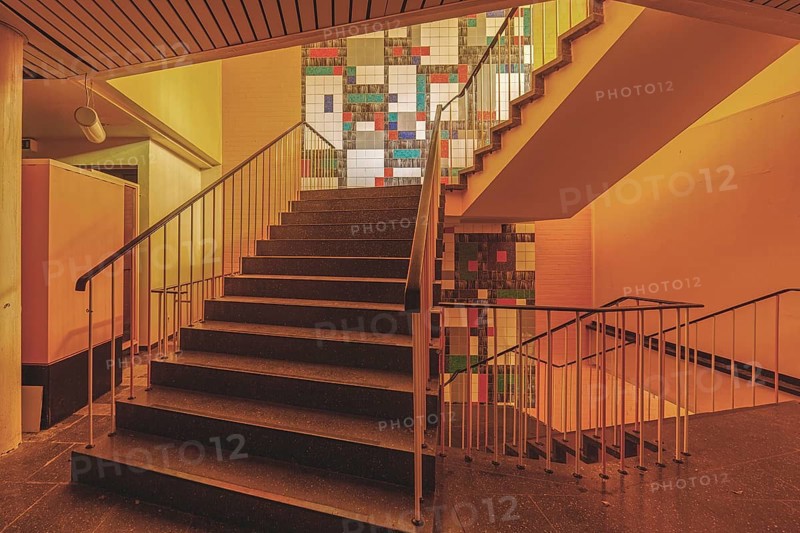Interior with a staircase and railings, illuminated by yellowish light and with wall art, Bad am Park, Lost Place, Essen, North Rhine-Westphalia, Germany, Europe