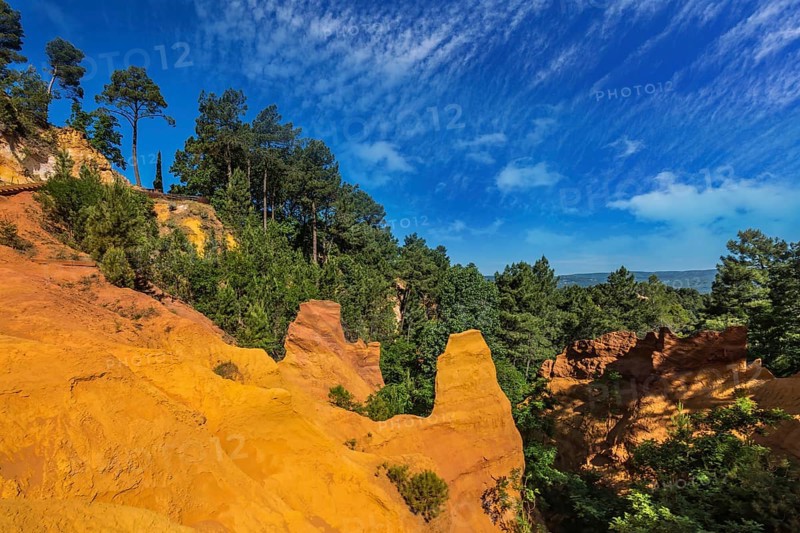 Multi-colored ocher outcrops - from yellow to orange-red. Green trees create a beautiful contrast with the ocher. Roussillon, Provence Red Village