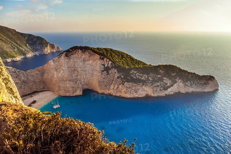The magical island of Zakynthos on the Mediterranean. The cove with a small sandy beach. The sky glows a warm sunset. Summer holidays in Greece. The concept of a summer beach holiday and photo tourism
