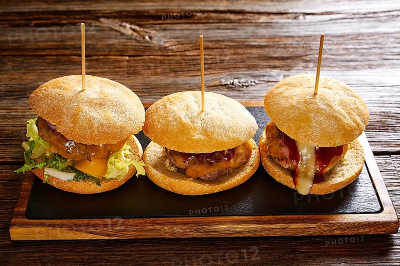 Burger in a row on a slate board and wood table