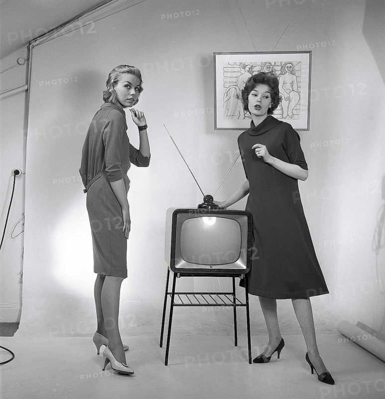 Television in the 1950s. Two young women are standing dressed in a typical 50s dress beside a televison set with an table antenna on top of it. In 1952 1.4 million households in Britain had a television. Photo Kristoffersson ref BZ26. Sweden 1952