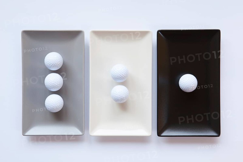 Different ceramic dishes with golf balls on over white background, rectangle dish
