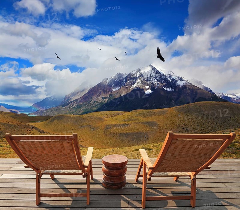 Pleasant holiday. Chile. Wooden chairs in the park Torres del Paine. On the horizon is visible snow-covered rocky mountain