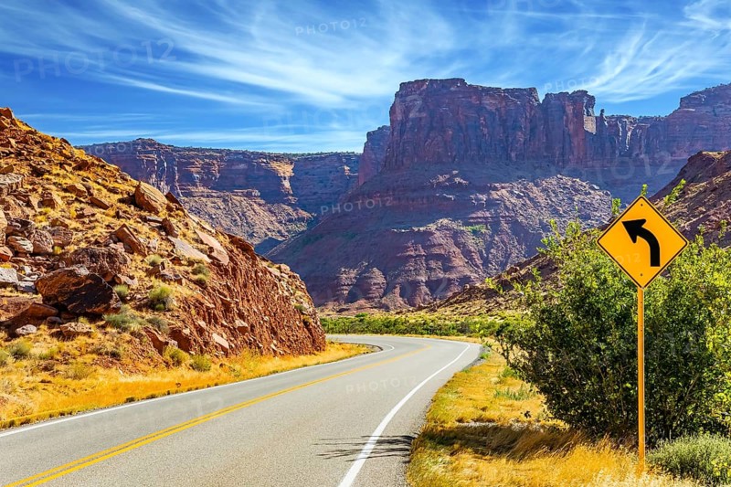 Wide asphalt highway among picturesque hills and rocks of bizarre shapes. The grandiose landscapes of America. Utah Red Sandstones. Fine autumn day