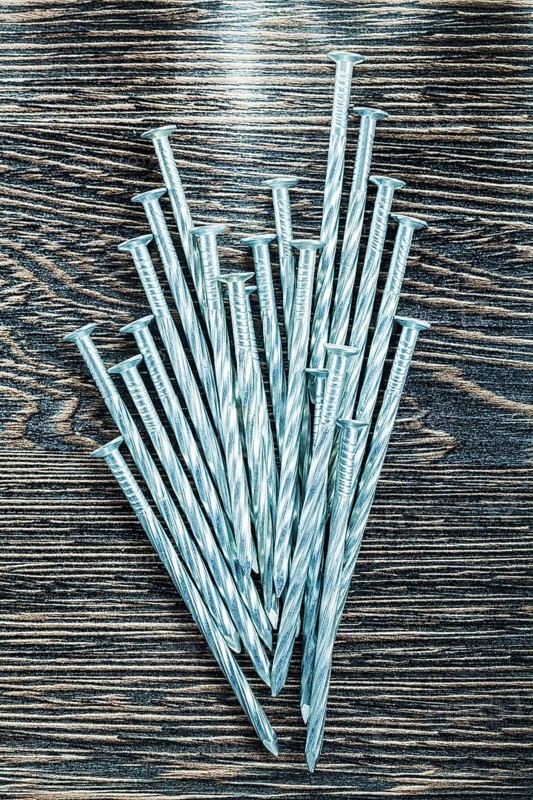 Heap of construction nails on wooden board