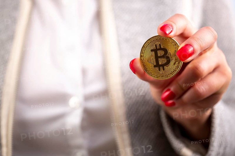 Virtual cryptocurrency money Bitcoin golden coin in the left hand of a woman with red nail polish. The future of money