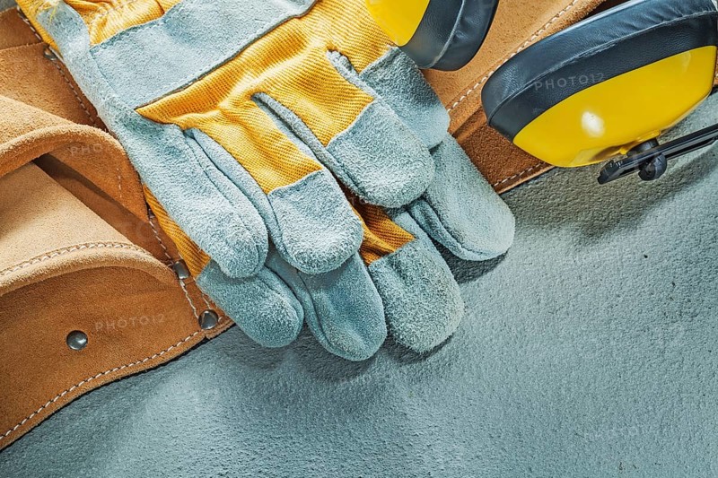 Set of leather tool belt protective gloves earmuffs on concrete background