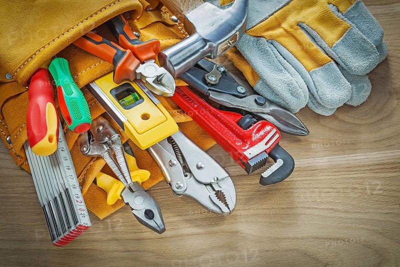 Tools in leather building belt on wooden board top view
