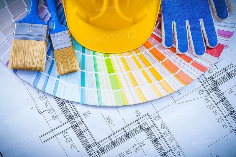Building helmet protective glove paint brushes and color sampler on blueprint construction concept