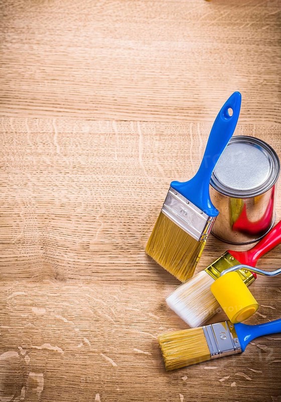 Organized copyspace three paint brushes roller can on wooden board construction concept