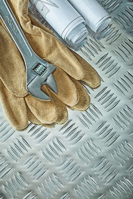 Blueprints adjustable spanner protective gloves on fluted metal sheet