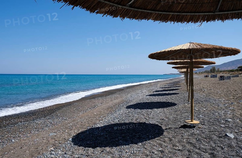 Tropical beach umbrellas providing sunshade for swimmers at an empty beach. Summer vacations. Paphos Cyprus