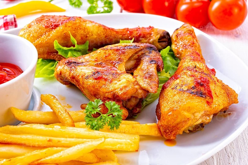 Grilled chicken wings, legs, chips and vegetables