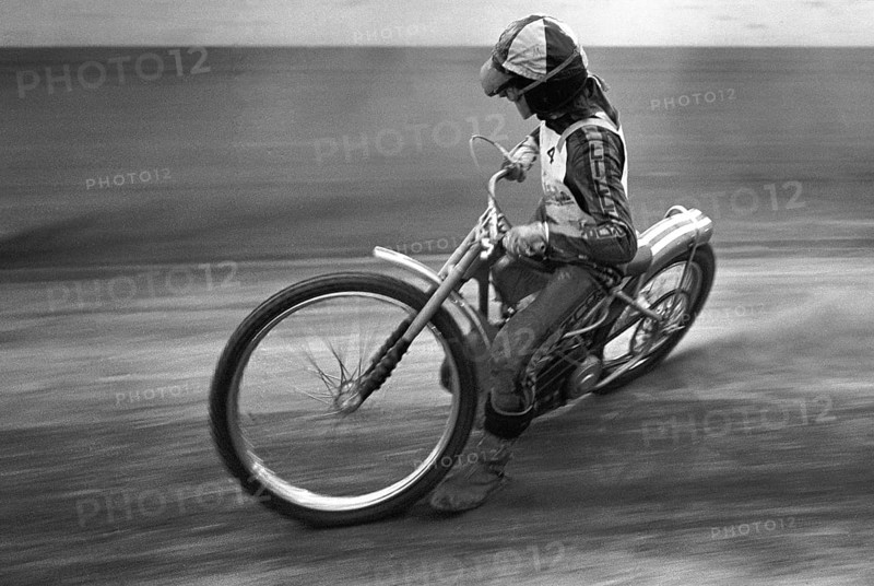 Speedway driver in the 1970s. The speedway motorcycle and driver is pictured racing on the speedway track in a high-speed