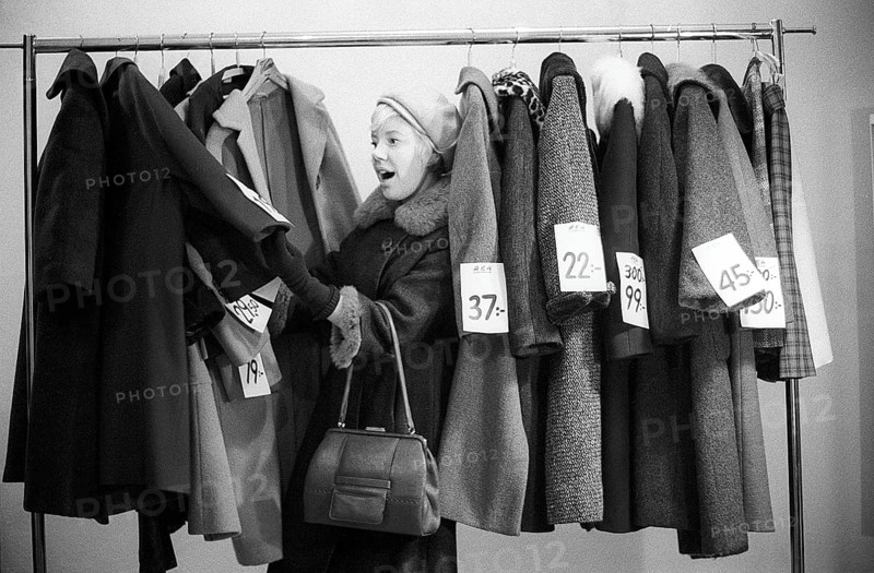 Great discounts of outerwear in the 1960s. A woman stands by a clothes rack, choosing from outerwear and coats marked with price tags with discounted prices. Judging by her face, she appreciates the reduced prices and thinks she's getting real bargains. Sweden January 1963. Ref CV28