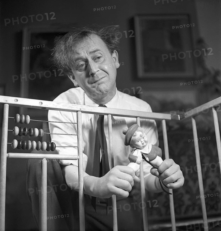 Father in the 1940s. Actor Åke Söderblom, 1910-1965 tries his best at amusing his son from outside the playpen playing with a a doll. Judging by the look on his face he has no success in cheering up his son. Sweden 1949 AN93-3